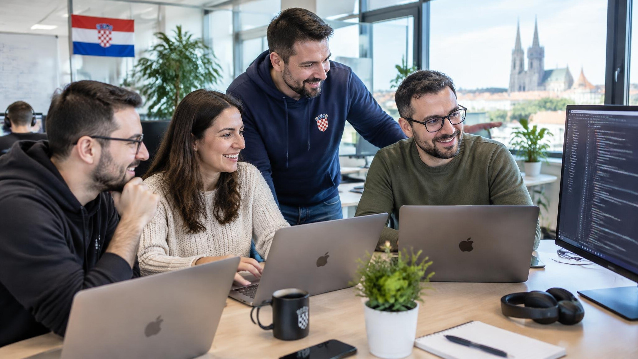 Team of colleagues collaborating around laptops in a bright office